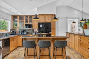a kitchen with wooden cabinets and a large island with bar stools at Waterfront Oasis with Pool, Hot Tub & Pet Friendly in Kelowna