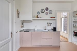 a kitchen with white cabinets and a sink at In de Pastorie Utrecht - Old rectory, just steps away from the city center in Utrecht +31 photos