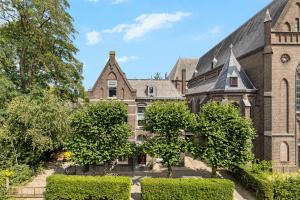 an old brick building with trees in front of it at In de Pastorie Utrecht - Old rectory, just steps away from the city center in Utrecht