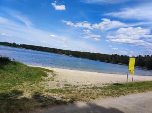 a yellow sign on a beach next to a body of water at Domki u Ani in Białka