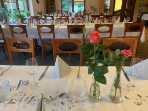 a dining room with white tables with vases of flowers at Hotel Pension Haus Stork in Holzhausen
