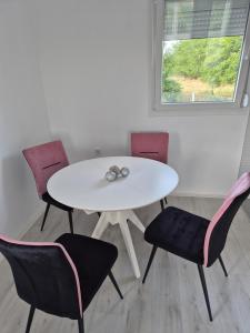 a white table and chairs with a white table and a window at Pećinska Vila in Kragujevac +4 photos
