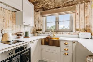 a kitchen with white cabinets and a sink at Nestledstays – The Nest in Binsted