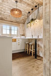 a kitchen with white cabinets and a counter with stools at Nestledstays – The Nest in Binsted