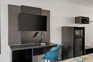 a room with a desk with a tv and a blue chair at Motel 6 - McComb, MS in McComb
