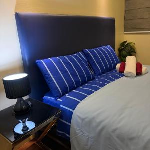 a bed with blue pillows and a lamp on a table at R2 condotel 2BR Santorini tower in Cainta