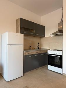 a kitchen with a white refrigerator and gray cabinets at Comfort Residence in Tuzi