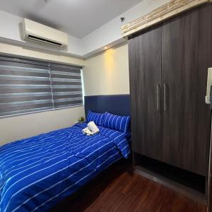 a bedroom with a blue bed and a cabinet at R2 condotel 2BR Santorini tower in Cainta