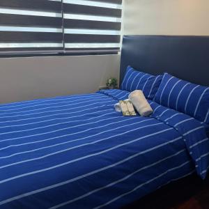 a blue bed with a blue comforter and a pillow at R2 condotel 2BR Santorini tower in Cainta