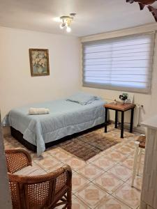 a bedroom with a bed and a window and a table at Apart Hotel Punto Real in Curicó