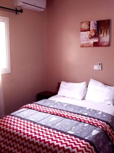a bed with a red and white blanket on it at Le MoniPol Hôtel in Franceville