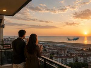 a man and a woman standing on a balcony looking at an airplane at SWEET HOME SUiTE HOTEL in Trabzon