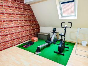a gym with exercise bikes and a brick wall at Appartement charmant et atypique, wifi, terrasse, jardin in Schleithal