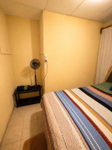 a bedroom with a bed and a table with a fan at Arianas Place 2 in Huehuetenango