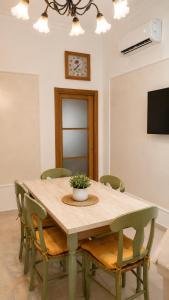 a dining room table with green chairs and a television at Terrazza Rossetti in Vasto