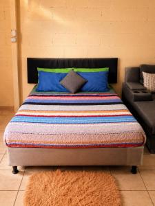a bed with blue pillows and a couch in a room at Arianas Place 2 in Huehuetenango