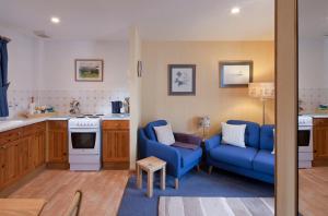a kitchen with two blue chairs and a blue couch at Shegarton Farm Cottages in Luss