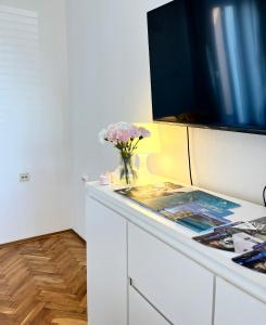 a vase of flowers on a counter with a tv at Falcon in Mali Lošinj
