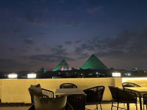 a group of tables and chairs with pyramids in the background at King's Gate Royal View INN in Cairo