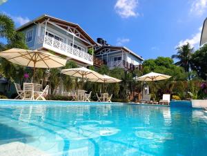 a large swimming pool with umbrellas in front of a house at Oasis Tolú Hotel Boutique in Tolú