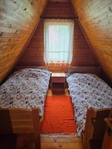 a bed in a wooden room with a window at Bungalows Dormire in Žabljak