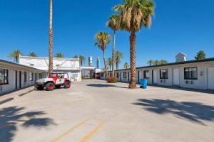 a parking lot with a tractor parked in front of palm trees at OYO Oasis Motel Las Vegas I-15 in Las Vegas