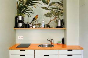 a kitchen with a sink and a bird on a wall at Les Jardins Blankenese in Hamburg +23 photos