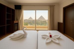 two swans sitting on a bed with a flower on it at King's Gate Royal View INN in Cairo