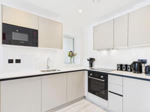 a white kitchen with white cabinets and appliances at Luxury Two Bed | Sleeps 6 | 5 beds in Brent Station +12 photos