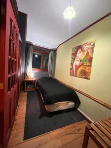 a bedroom with a bed and a painting on the wall at Amura Hostel in Puerto Varas