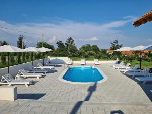 a pool with chaise lounge chairs and a group ofiuses at Pećinska Vila in Kragujevac