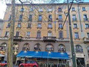 a large building with a blue awning in front of it at Appartamento Duomo-Monte Nero in Milan