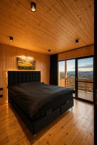 a bedroom with a bed in a room with windows at Sunset Hill Chalet Sighișoara in Sighişoara