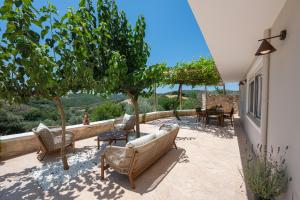 a patio with chairs and tables and trees at CASA di FLORI in Epáno Flória