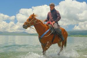 a man riding a horse in the water at Horse Riding Son-kol in Song-Kul