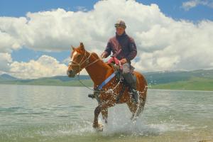a man riding a horse in the water at Horse Riding Son-kol in Song-Kul