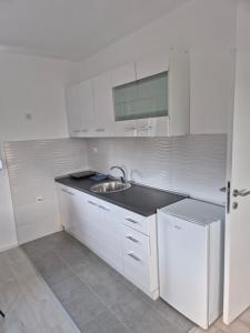 a white kitchen with a sink and a refrigerator at Pećinska Vila in Kragujevac