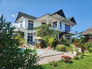 a large white house with flowers and plants at Maneri Villa and Apartments in Zanzibar City