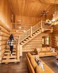 a woman walking up a staircase in a log cabin at Blue Moose Private pool spa sauna lake access in Wentworth