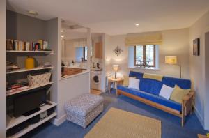 a living room with a blue couch and a kitchen at Shegarton Farm Cottages in Luss