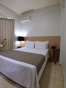 a bedroom with a large bed and a person taking a picture at Corumbá Plaza Hotel in Luziânia