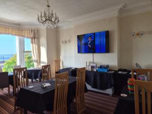 a dining room with two tables and a chandelier at St. Hilary Guest House in Llandudno