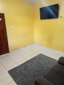a living room with a couch and a tv on the wall at Casa Fronteira in Oiapoque