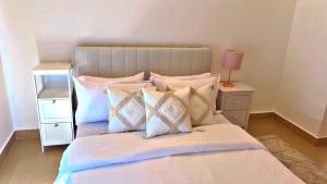a bedroom with a bed with pillows and a lamp at Two Bedroom Moyoni Apartment in Mchamba Wima