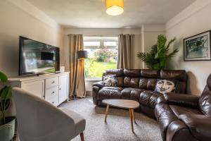 a living room with a leather couch and a television at 3 Bedrooms house ideal for long Stays! in Southampton