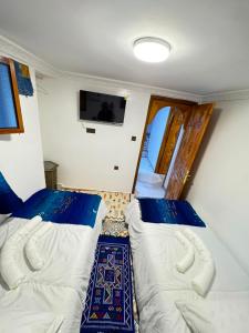 a room with two beds and a tv on the wall at FATI GUEST HOUSe in Chefchaouen +29 photos
