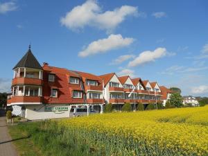 una fila de edificios de apartamentos con un campo de flores amarillas en Aparthotel HAUS USEDOM, en Kolpinsee