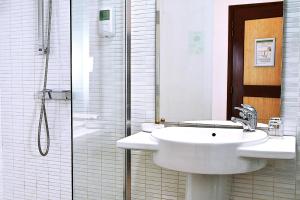 a white bathroom with a sink and a shower at Ganalé Hôtel in Dakar +37 photos