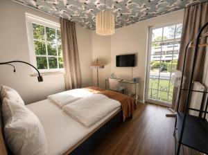 a bedroom with a bed and a window and a tv at Les Jardins Blankenese in Hamburg