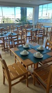 a dining room with tables and chairs and windows at Corumbá Plaza Hotel in Luziânia